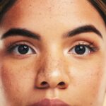 Woman, skin and closeup in studio portrait with beauty, cosmetics and natural glow on face by backg