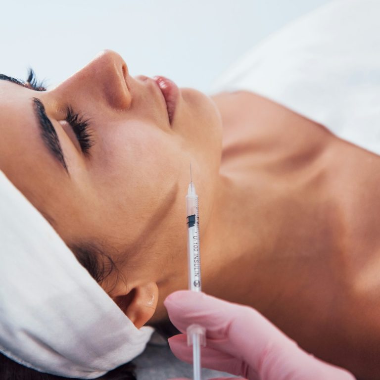 Woman that lying down in spa salon and have injection by the syringe into her face skin
