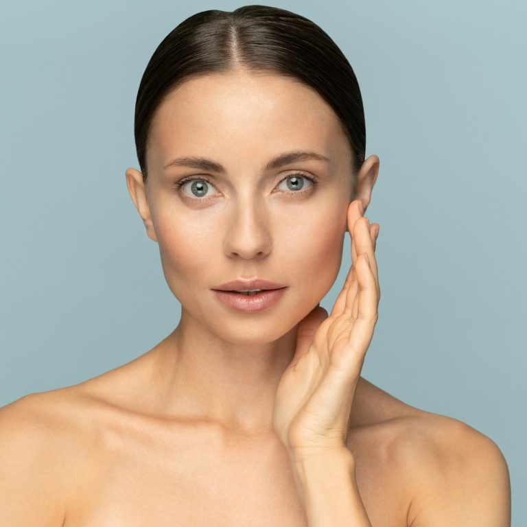 Woman with natural makeup, combed hair, touching well-groomed pure skin on face. Beauty, facelift